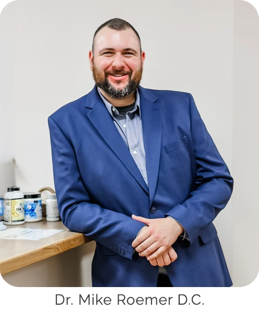 Dr. Mike Roemer wearing a suit and leaning against the counter
