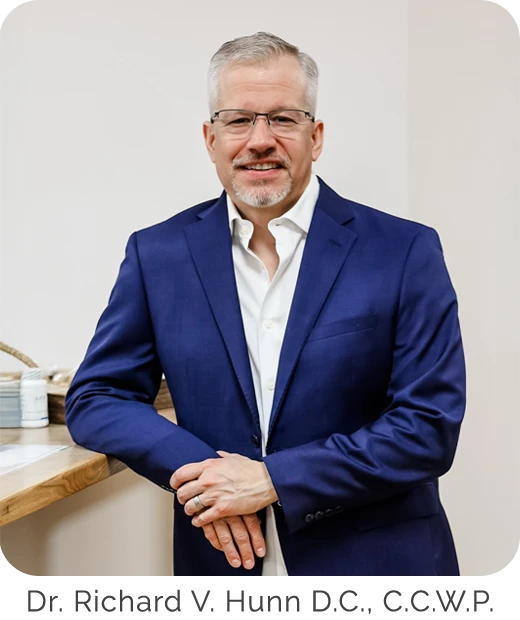 Dr. Richard Hunn wearing a suit and leaning against the counter